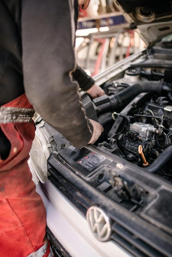 Un mecánico trabaja con las manos sobre el motor destapado de un carro.